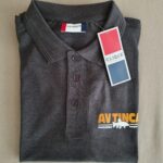 Ein gefaltetes, dunkelgraues Poloshirt mit Kragen und drei Knöpfen, mit einem CLIQUE-Tag und einem orange-weiß gedruckten Text auf der Brust.